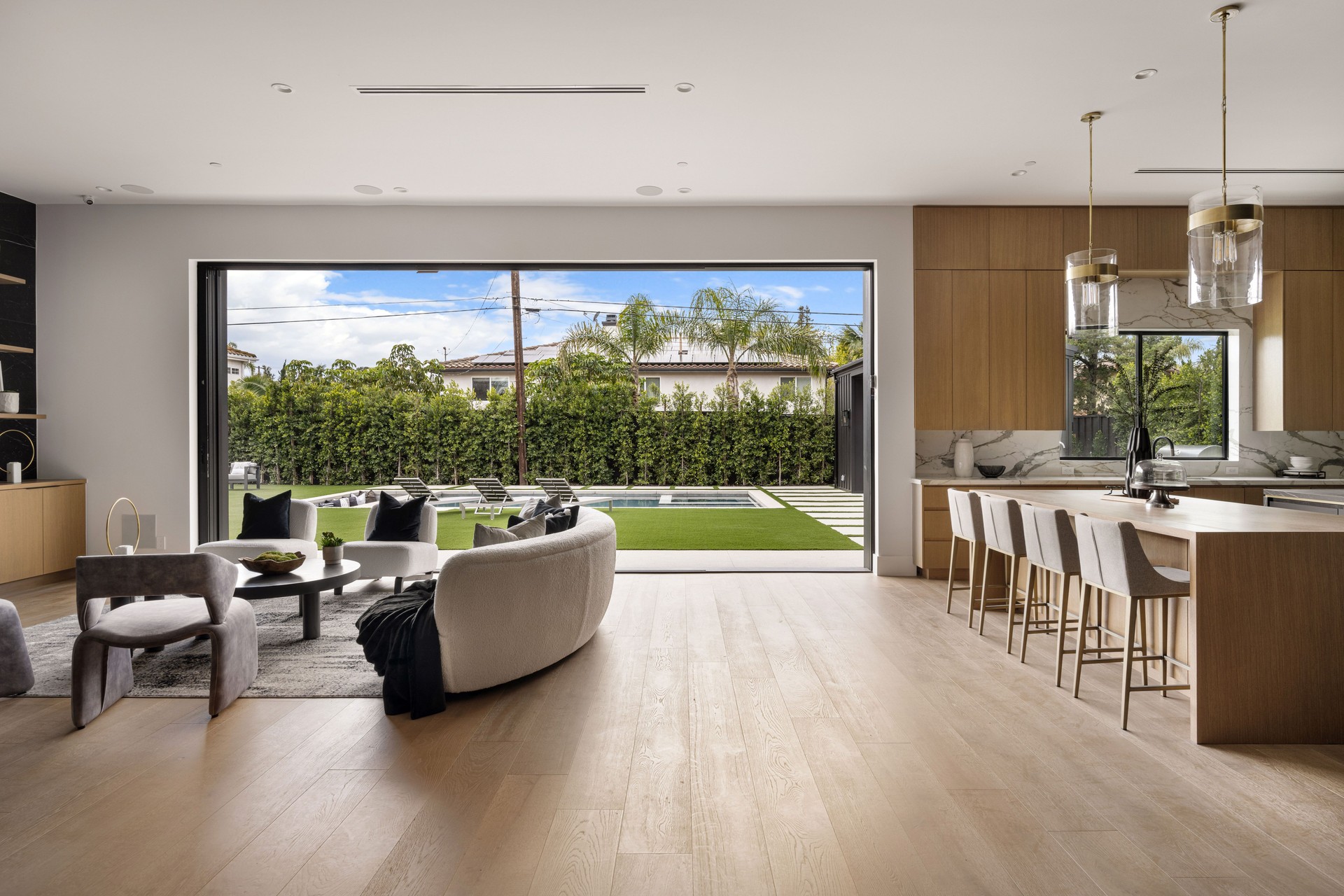 Modern open-plan living room and kitchen with backyard view